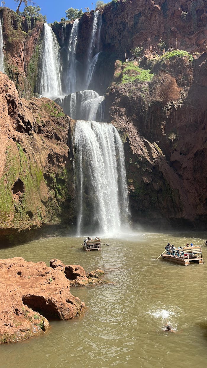 gallery-03 Capture of Ouzoud Waterfalls with tourists enjoying boat rides under the bright sun.